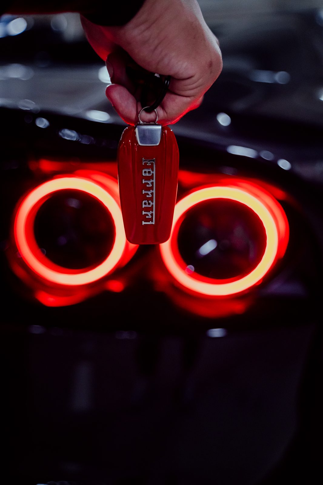 Ferrari key held against the glow of the taillights