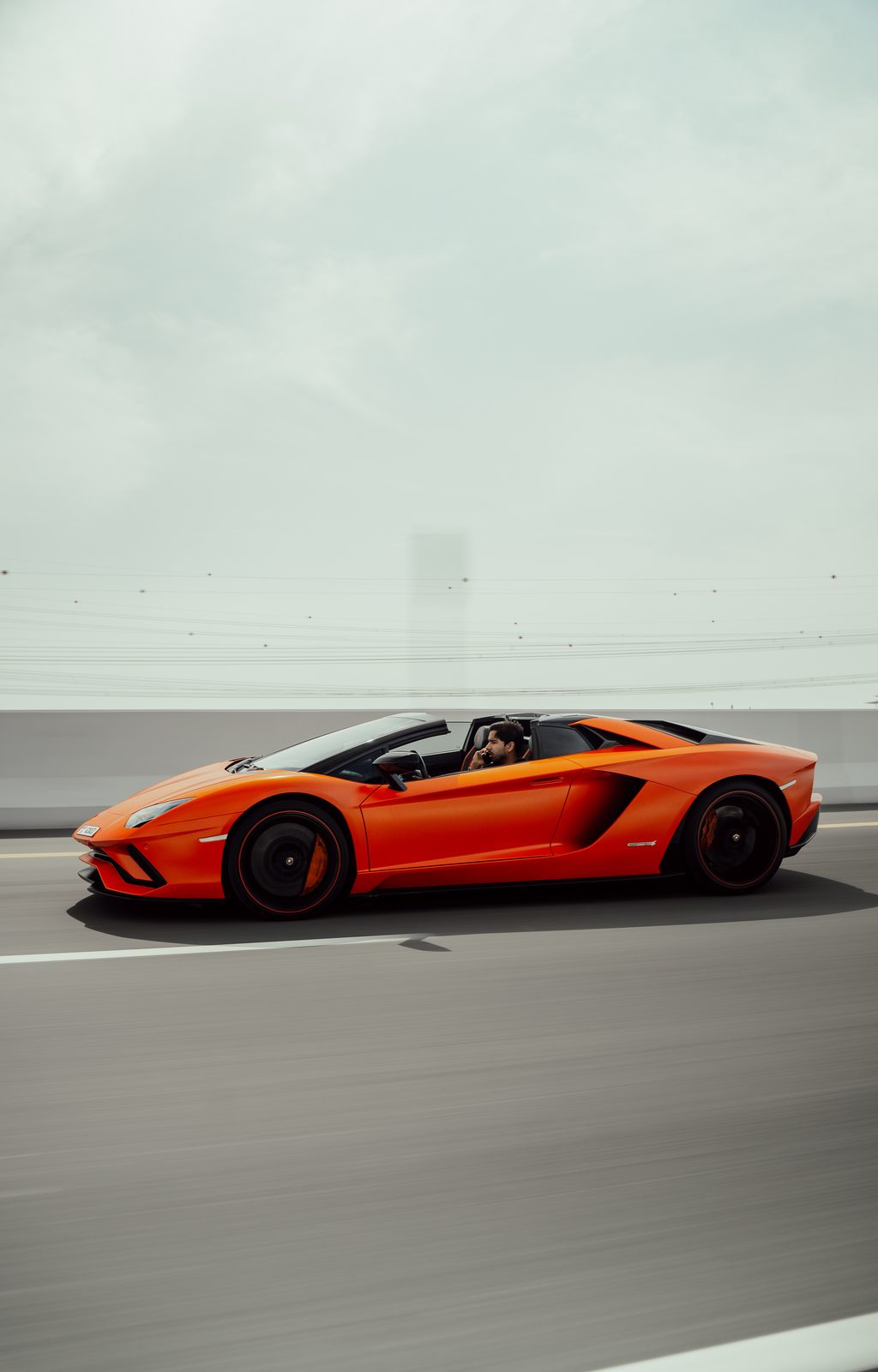 Orange Lamborghini Aventador S Roadster side profile at speed, roof off