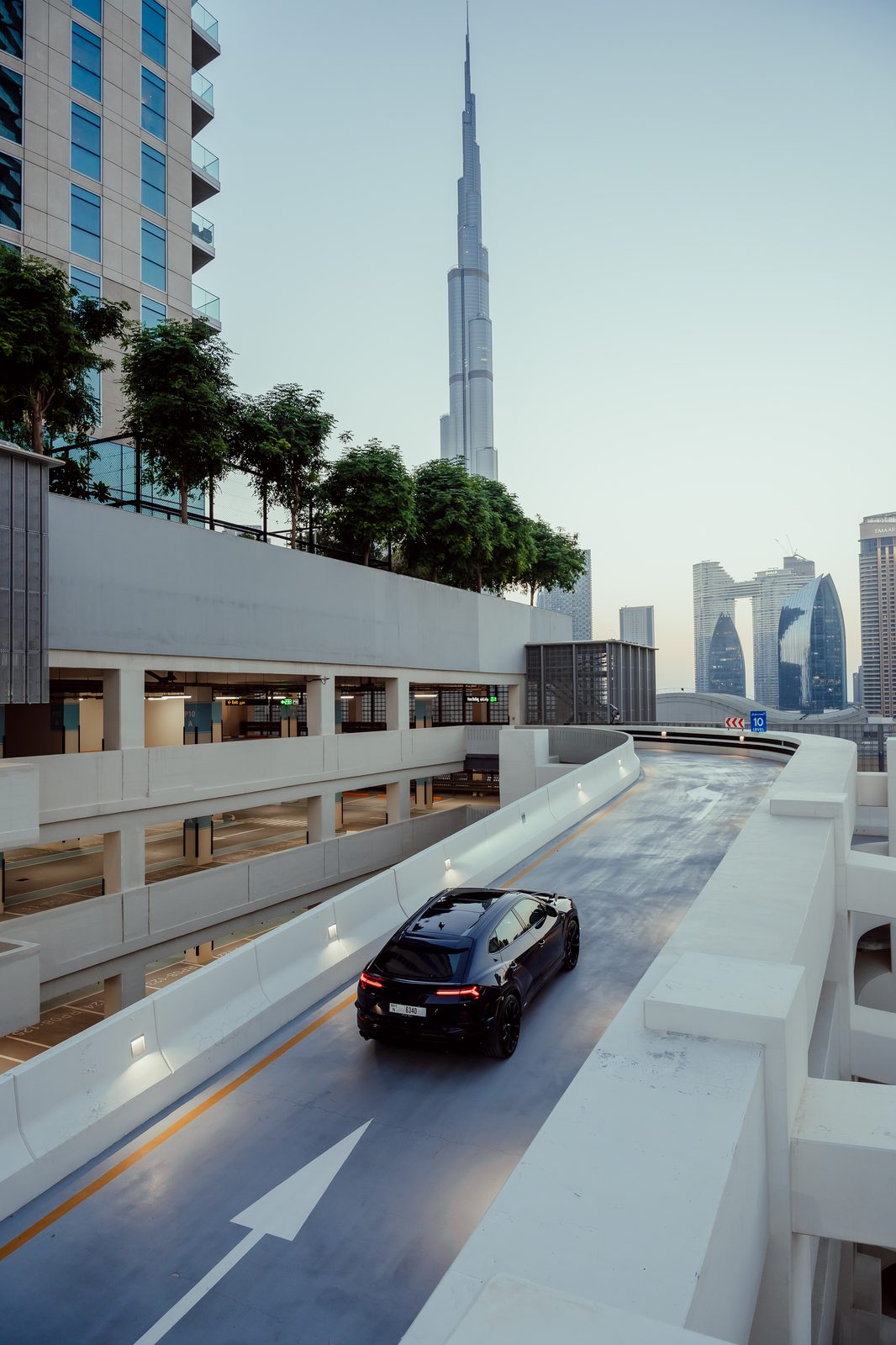 Black Lamborghini Urus on a parking ramp beneath the Burj Khalifa