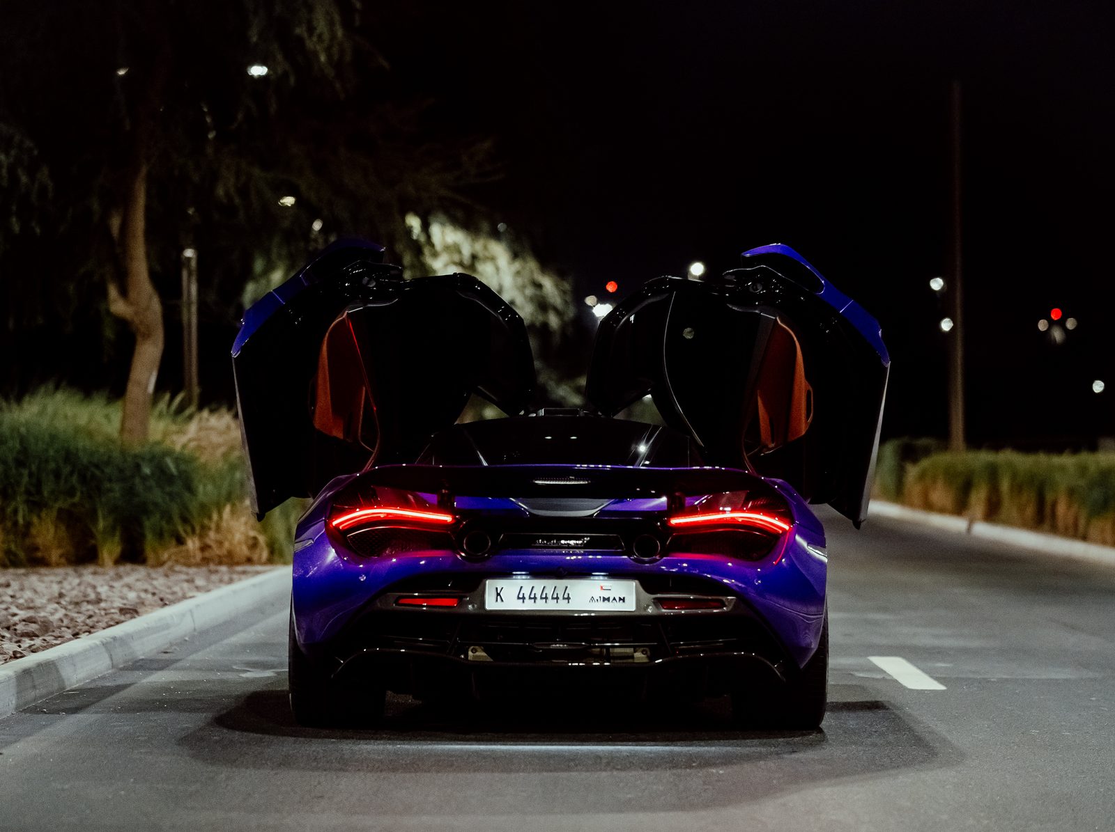 Purple McLaren 720S with both doors raised at night