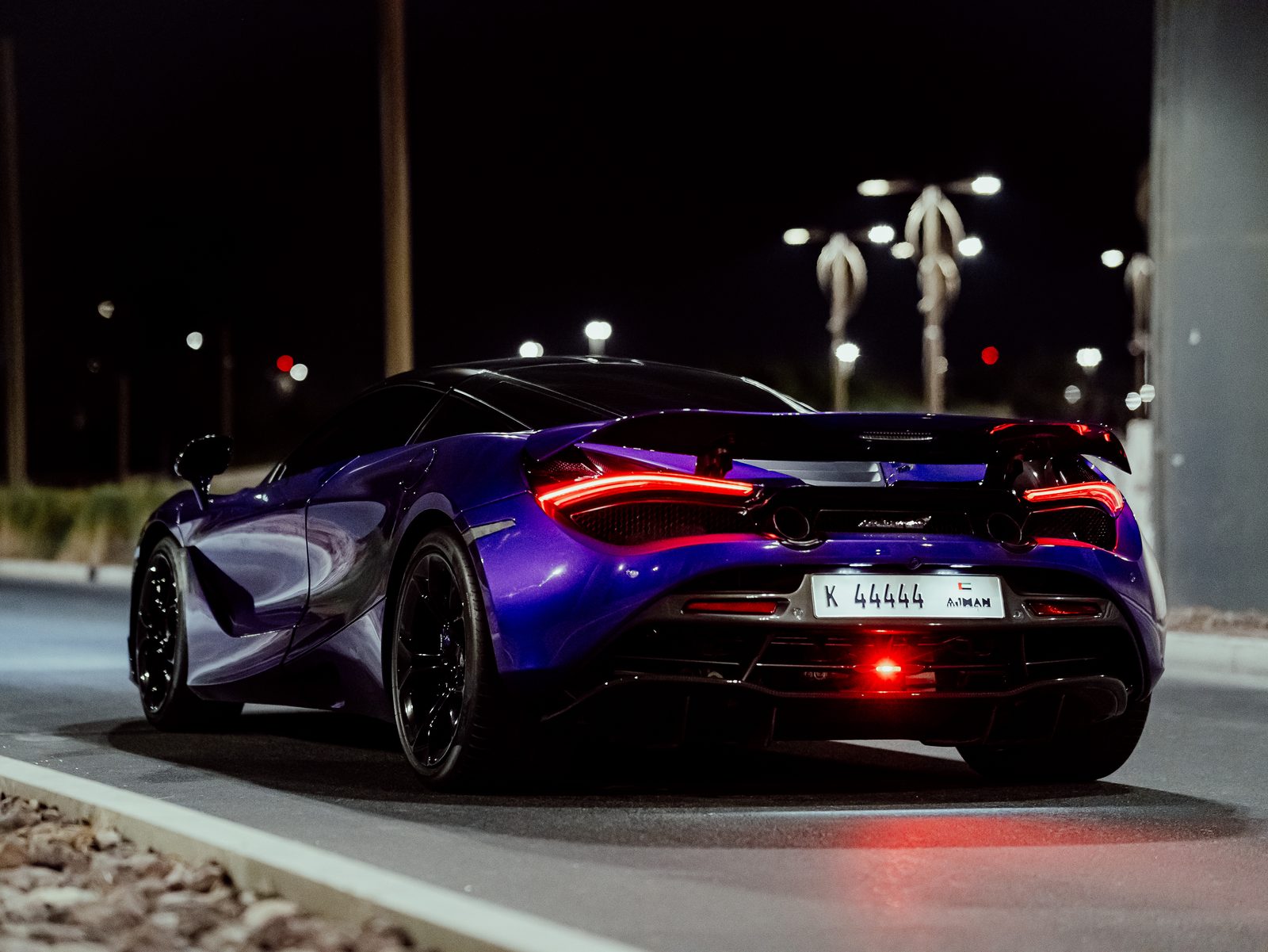 Purple McLaren 720S rear three-quarter at night in Ajman