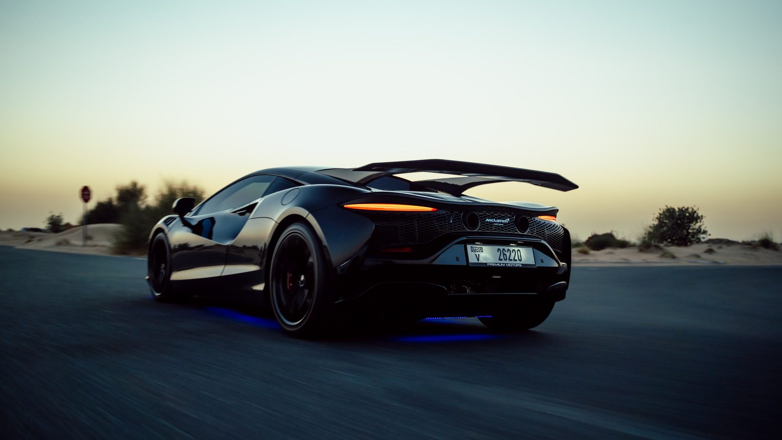 Black McLaren Artura rolling at dusk on a desert road outside Dubai