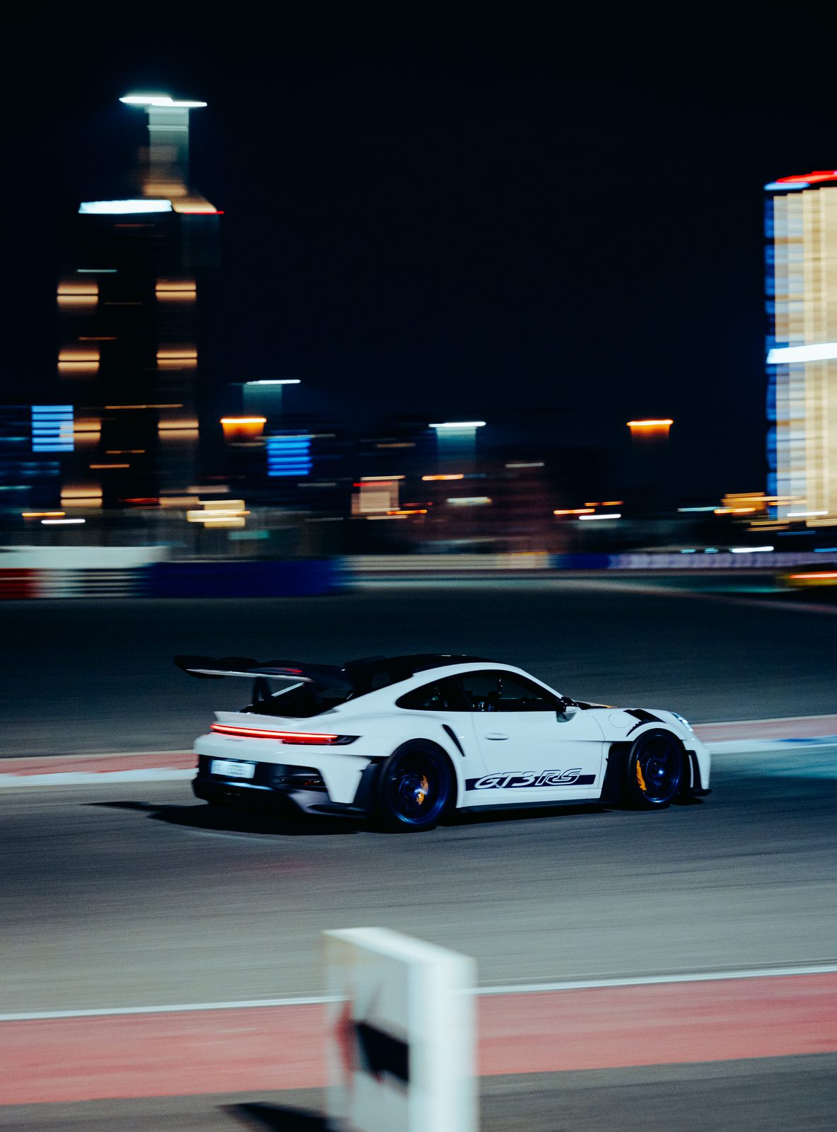 White Porsche 911 GT3 RS panning past the Dubai Autodrome towers at night