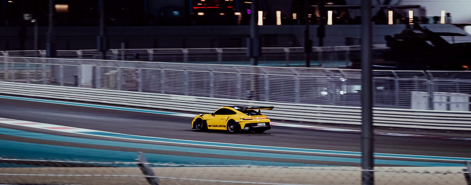 Yellow Porsche 911 GT3 RS at speed on the Yas Marina Circuit at night